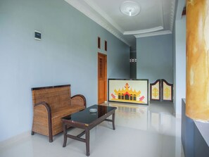 A room with a sofa, a table, a wall-mounted TV, and a decorative screen. - OYO 89999 Hotel Bumi Kedaton Resort (Bandar Lampung)