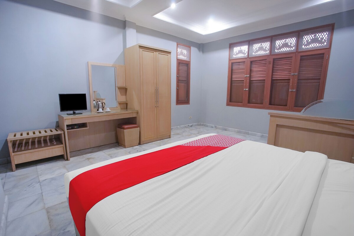 Ein Schlafzimmer mit einem Bett, einem Schreibtisch, einem Kleiderschrank und einem Fernseher.