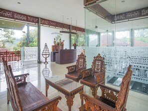 Un espace d’accueil doté d’une cloison en verre, de meubles en bois et d’un mur décoratif orné de motifs complexes.