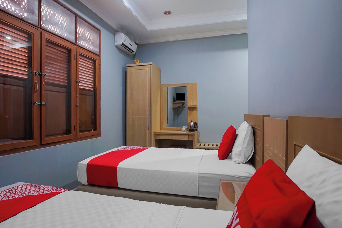 Ein Hotelzimmer mit zwei Betten, einem Kleiderschrank, einem Spiegel und einer Klimaanlage.