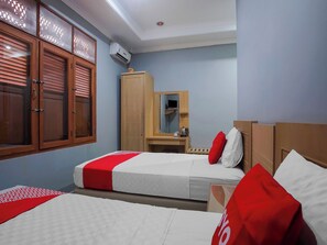 Une chambre d’hôtel avec deux lits, une armoire, un miroir et un appareil de climatisation.