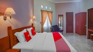 A hotel room with a large bed, two bedside lamps, a chair, a wardrobe, and a mirror. - OYO 89999 Hotel Bumi Kedaton Resort (Bandar Lampung)