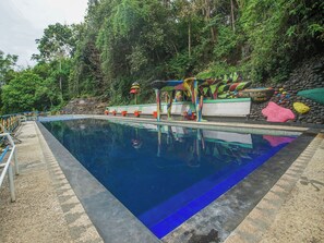 A swimming pool with a stone wall and colorful rock decorations. - OYO 89999 Hotel Bumi Kedaton Resort (Bandar Lampung)