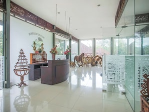 Un área de recepción con mostrador, elementos decorativos y un panel de vidrio con diseños estampados.