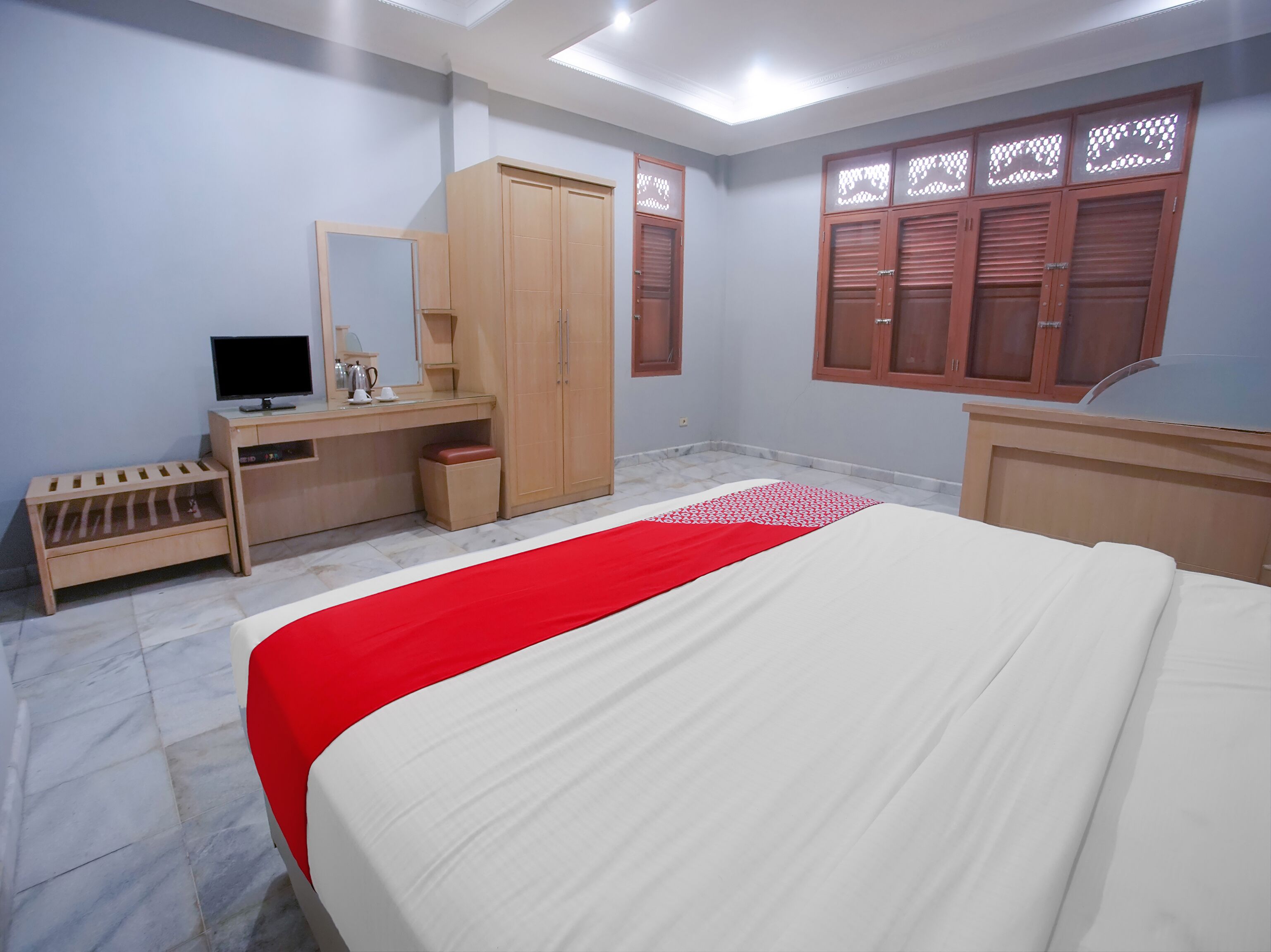 A bedroom with a bed, a desk, a wardrobe, and a television.