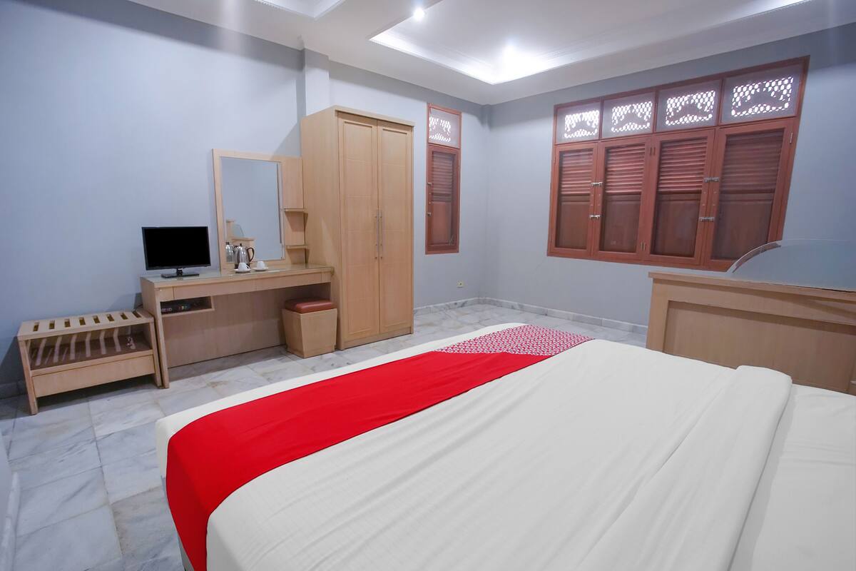 Ein Schlafzimmer mit einem Bett, einem Schreibtisch, einem Kleiderschrank und einem Fernseher.