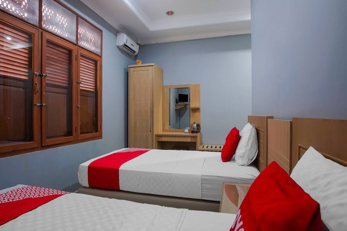 Ein Hotelzimmer mit zwei Betten, einem Kleiderschrank, einem Spiegel und einer Klimaanlage.