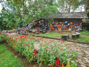 Un jardín con un sendero de piedra, flores coloridas y un mural en un edificio.