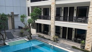 A modern building with a swimming pool, multiple balconies, and outdoor seating areas. - Bintang Mulia Hotel (Jember)