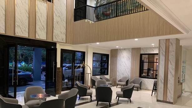 A spacious lobby with modern furniture, a staircase, and large windows offering a view of the street. - Bintang Mulia Hotel (Jember)