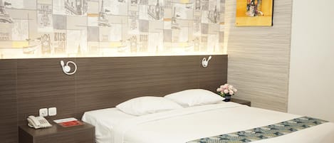 Una habitación de hotel con una cama grande, ropa de cama blanca, una mesita de noche con teléfono, una pared con papel tapiz de paisaje urbano y un cuadro sobre la cama.