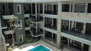 A multi-story hotel with balconies, a swimming pool, and outdoor seating areas. - Bintang Mulia Hotel (Jember)