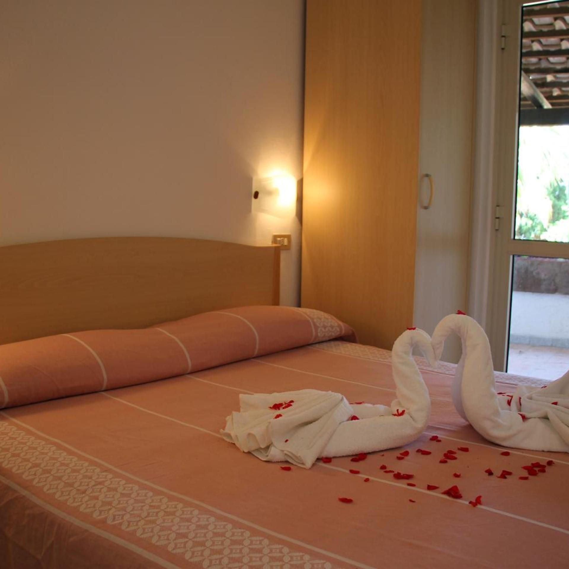 A hotel room with a bed, a wall-mounted light, and a door leading outside.