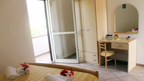 A hotel room with a bed, a desk, a chair, a wardrobe, and a large window. - Hotel Incoronato (Capo Vaticano)
