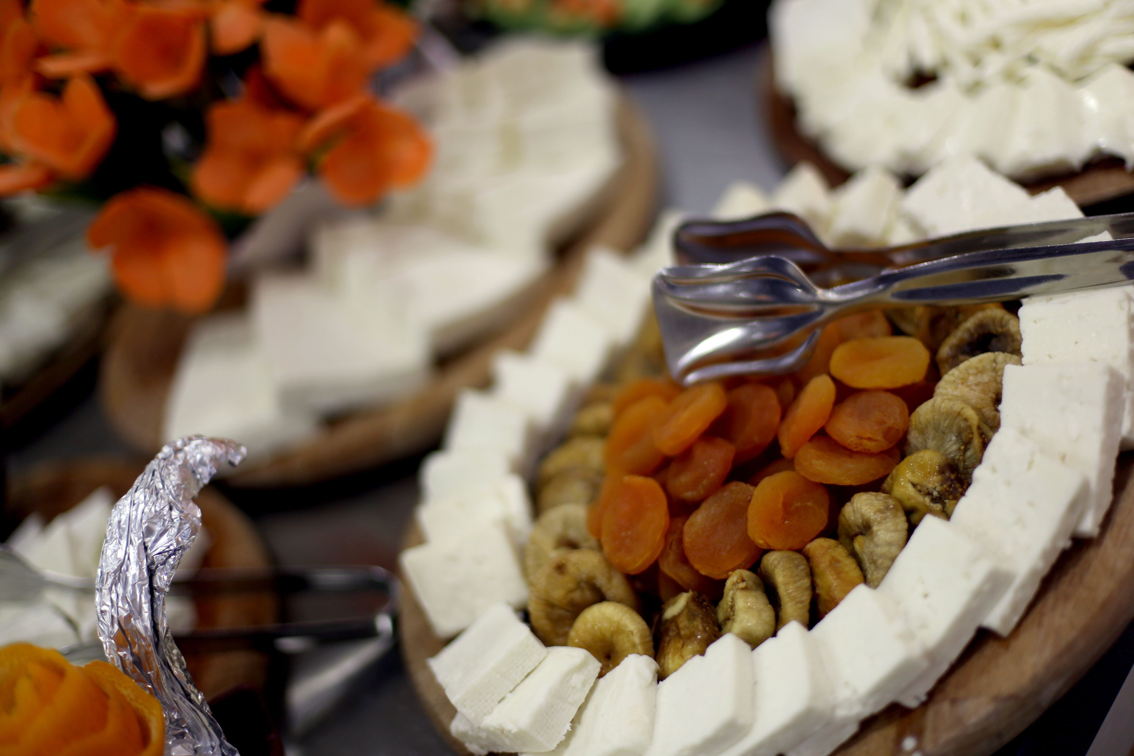 A variety of food items including nuts, dried fruits, and cheese arranged on a wooden board.