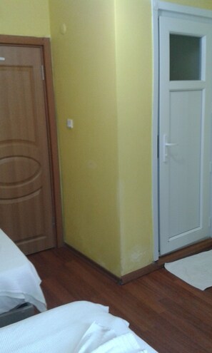 A room with a wooden door, a white door, and a bed with white bedding. - Bereket Apart Hotel (Istanbul)