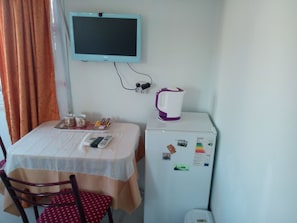 A small room with a table, chairs, a television, a refrigerator, and a kettle. - Bereket Apart Hotel (Istanbul)