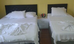 A hotel room with two beds, each with white linens and pillows. There is a small bedside table with a fruit bowl on it. - Bereket Apart Hotel (Istanbul)