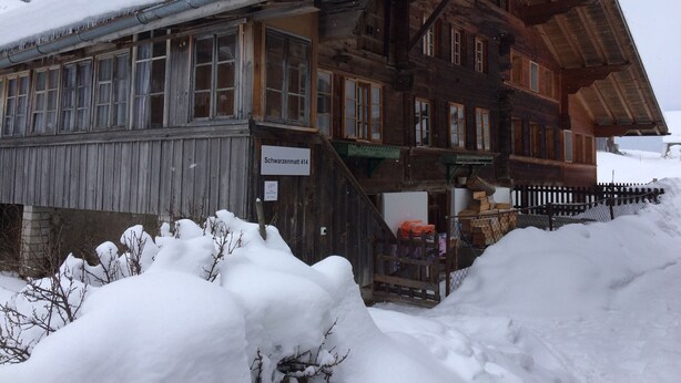 A wooden building with a snow-covered roof and a sign reading "Schwarzmatt 414". - 400 Year Old Swiss Chalet (Boltigen)