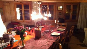 A dining table set with plates, a candle holder, and a vase with flowers. - 400 Year Old Swiss Chalet (Boltigen)