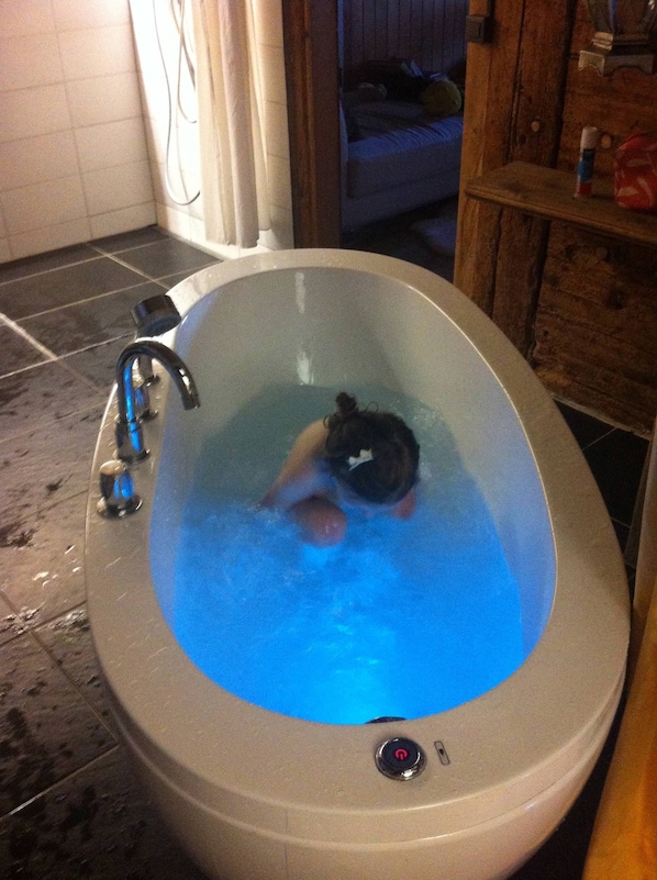 A bathtub with a person inside, a faucet, and a control button.