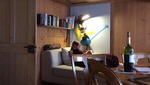 A cozy room with wooden walls and a sofa. There's a table with a bottle and a lamp. - 400 Year Old Swiss Chalet (Boltigen)