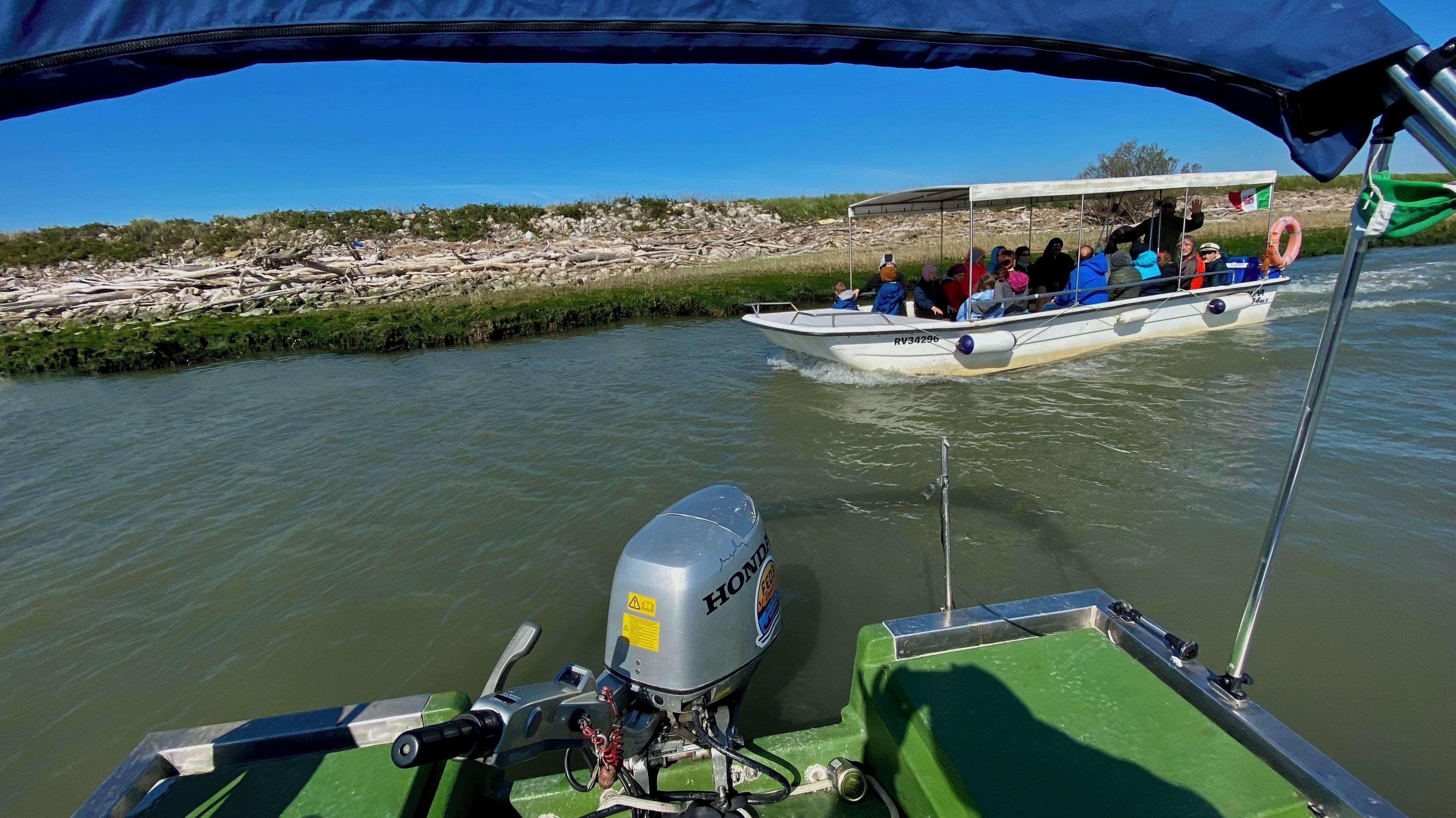 Een boot met passagiers en een groene constructie op de voorgrond.