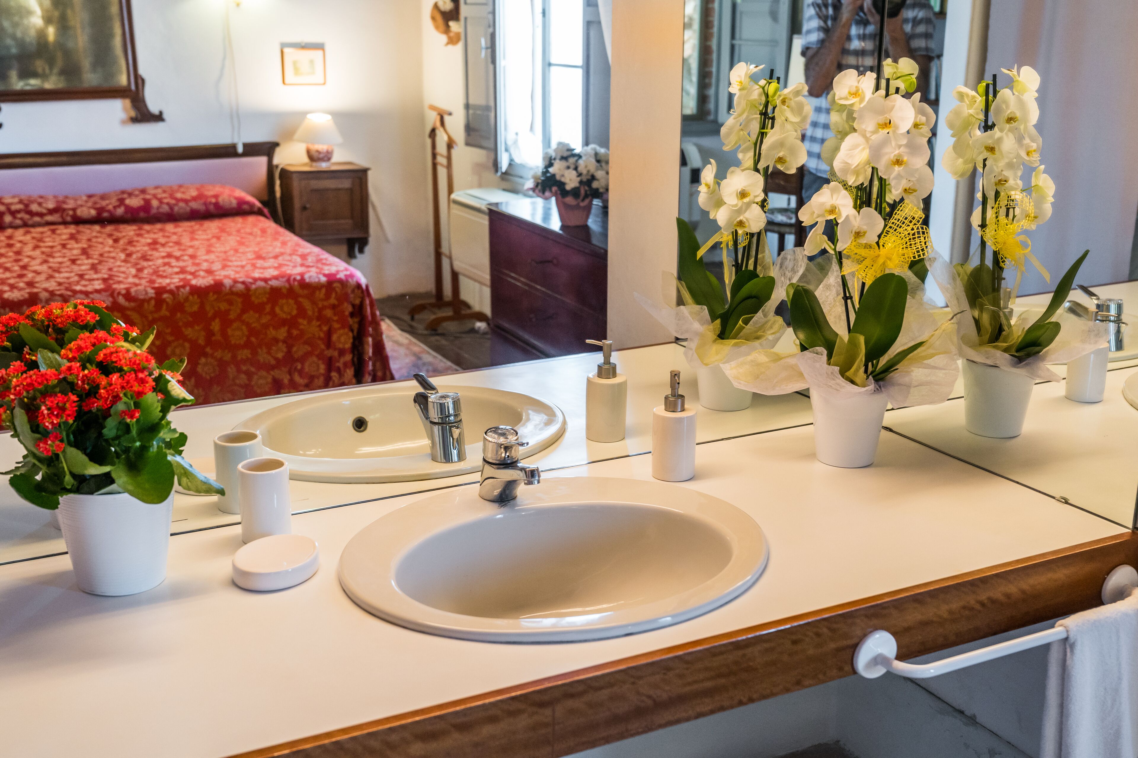 Un bagno d'hotel con uno specchio grande, due lavabi e un letto con lenzuola rosse.