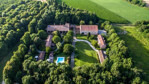 Luchtbeeld van een groot landgoed met meerdere gebouwen, een zwembad en veel groen.