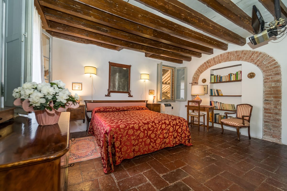 Une chambre à coucher avec un lit, des tables de chevet, un bureau et une bibliothèque.