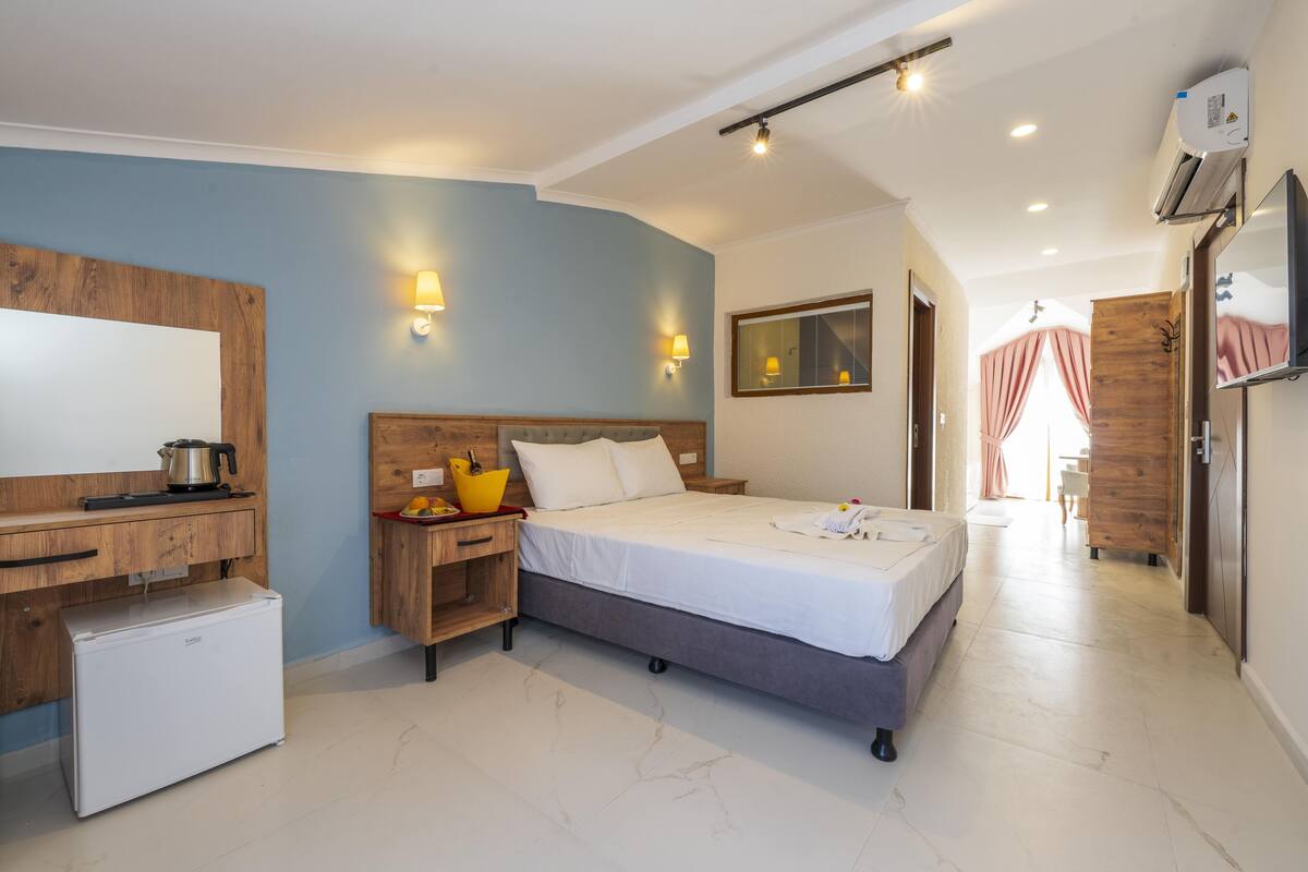 A bedroom with a bed, bedside table, and a small refrigerator.