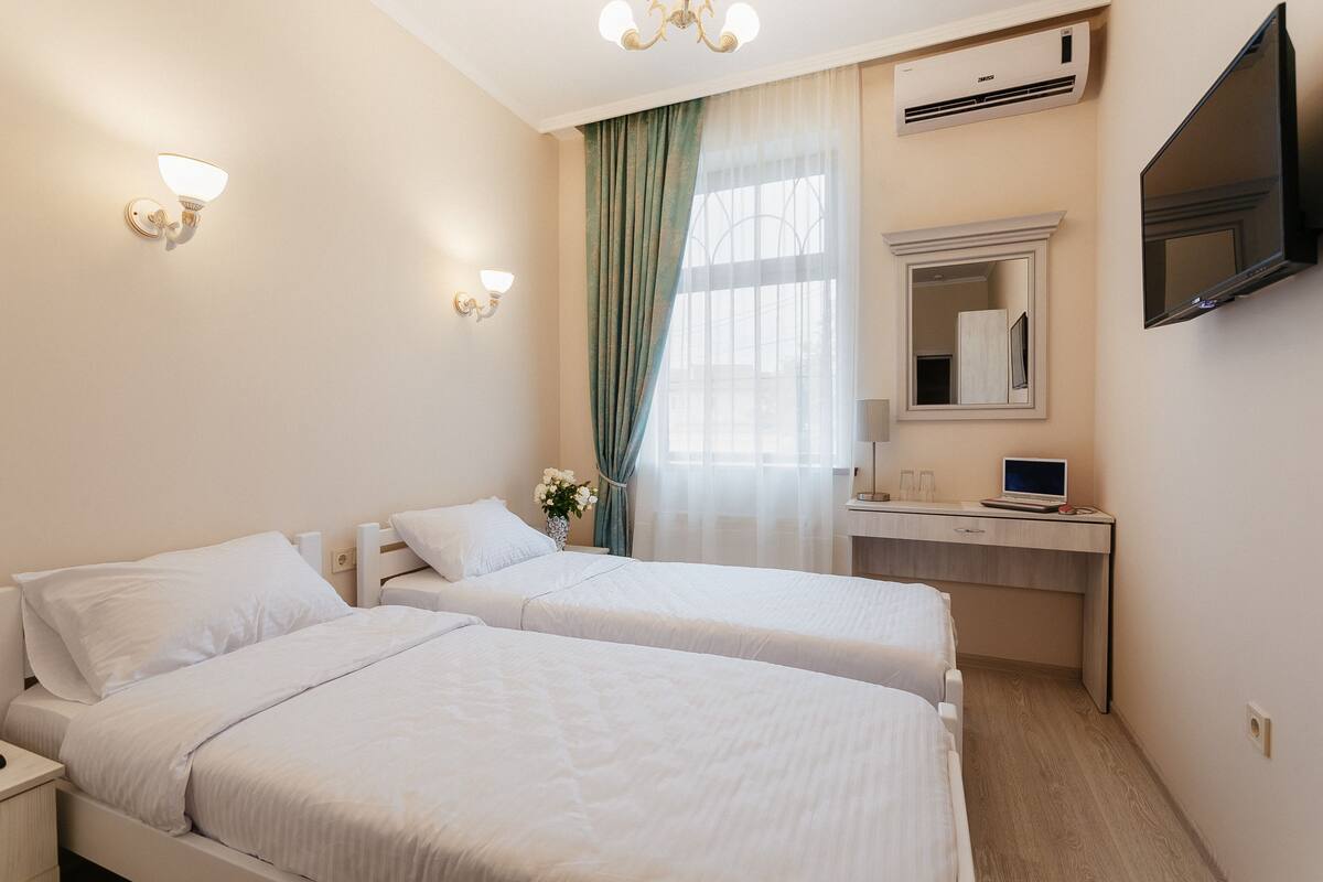 A hotel room with two beds, a desk with a computer, a TV, and a mirror.