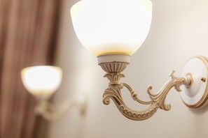 A wall-mounted light fixture with a frosted glass shade and ornate metalwork. - Asiya Hotel (Odesa)