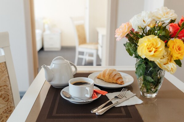 A breakfast setup with a teapot, cup, croissant, and a vase of flowers on a table. - Asiya Hotel (Odesa)