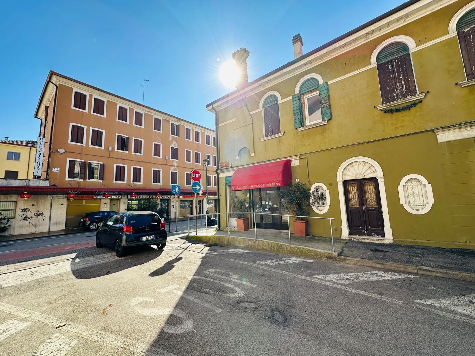 A street view with a building featuring a red awning, a stop sign, and a bicycle lane.
