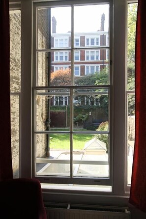 A window with a view of a building and greenery. - The Ridgemount Hotel (London)