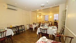 Comedor con varias mesas dispuestas para comidas, sillas y un mostrador tipo buffet.
