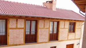 A two-story building with a red-tiled roof, wooden balconies, and a brick facade.