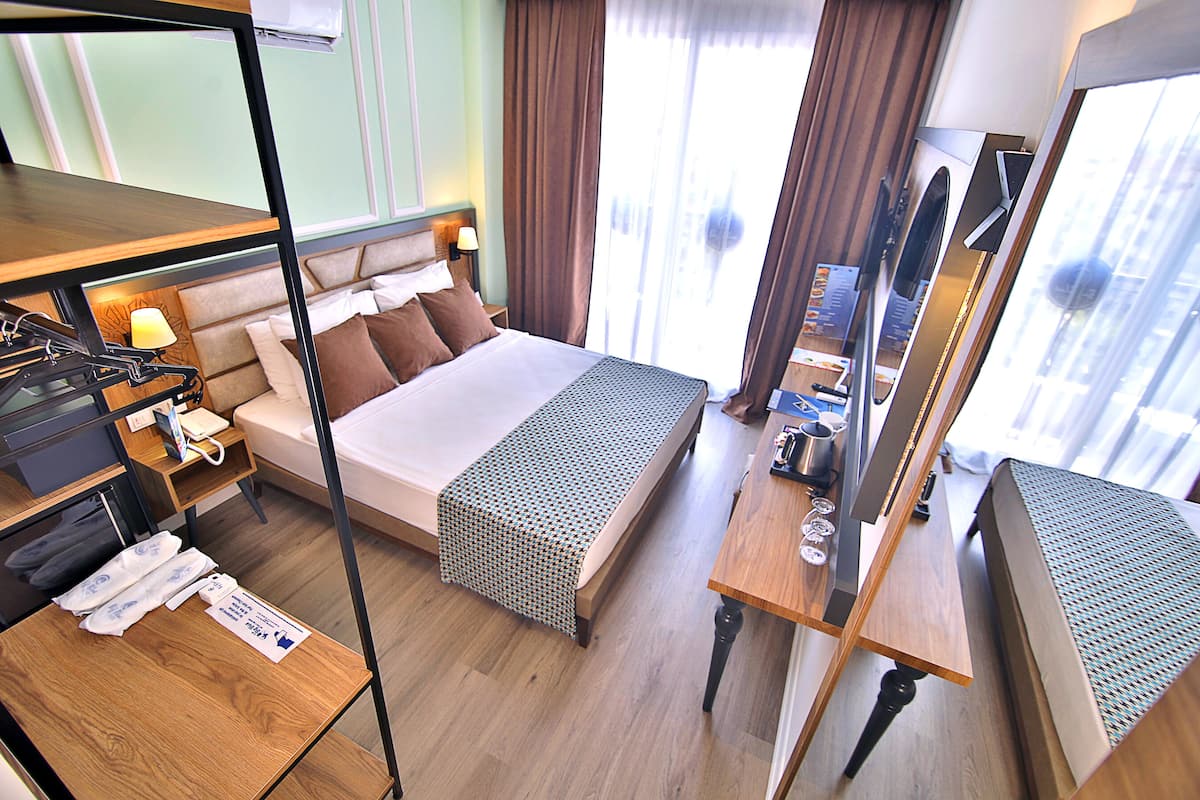 Une chambre d’hôtel comprenant un lit, une table de chevet, une lampe et un bureau avec une chaise.