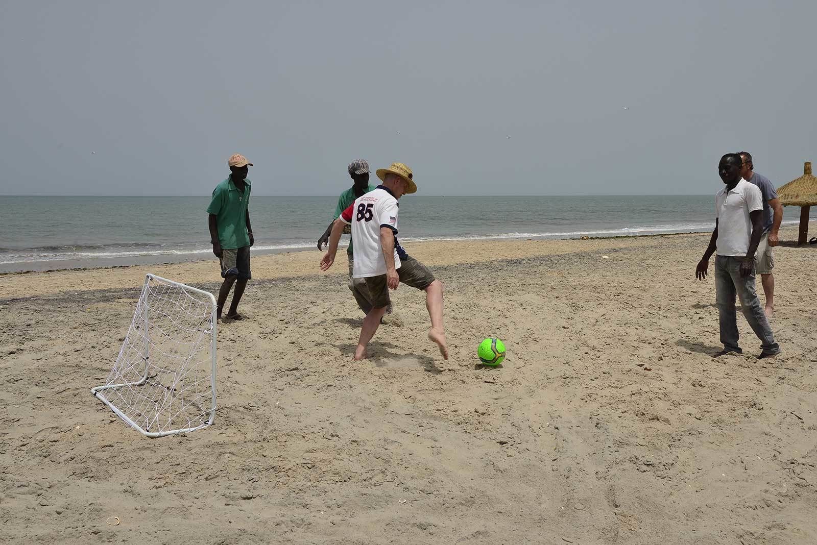 A sandy beach with a goalpost and a soccer ball.