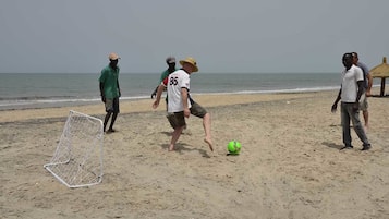 Ein sandiger Strand mit einem Fußballtor und einem Fußball.