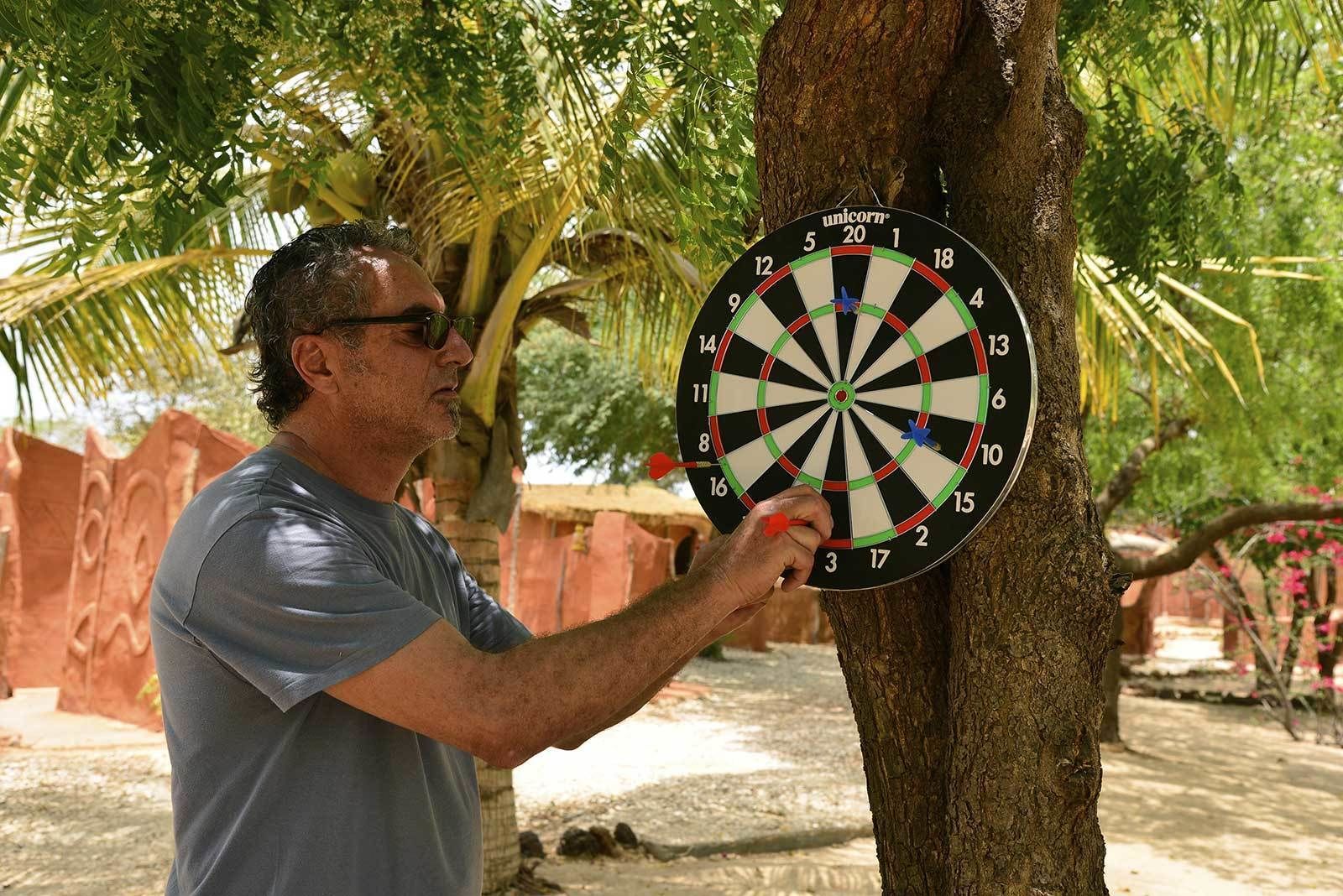 A man playing darts at a tree.