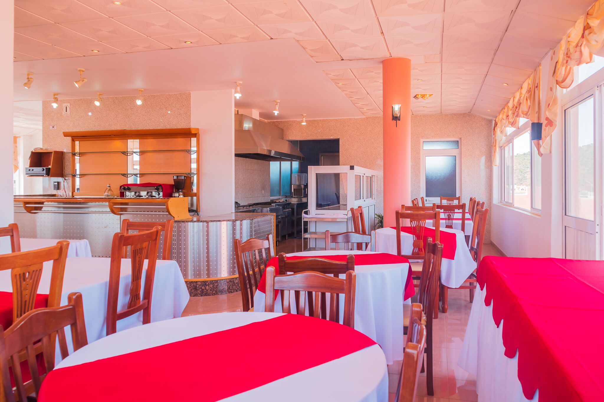 Un restaurante con mesas redondas, manteles rojos y sillas de madera.