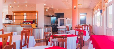 Un restaurante con mesas redondas, manteles rojos y sillas de madera.