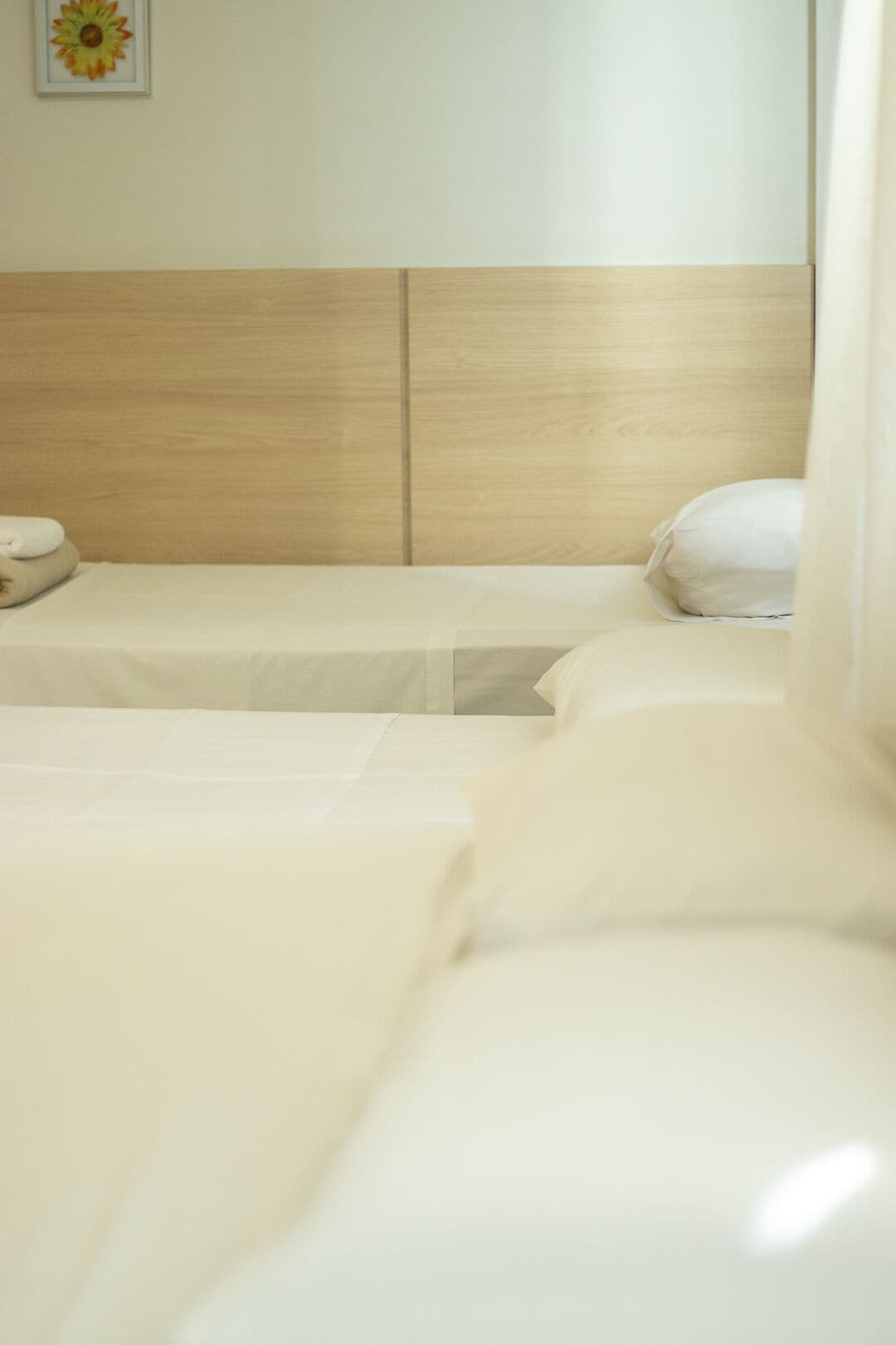 Una habitación de hotel con dos camas, cabecera de madera y un cuadro en la pared.