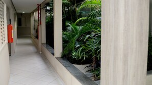 Un pasillo con suelo de baldosas, un extintor y plantas en macetas.