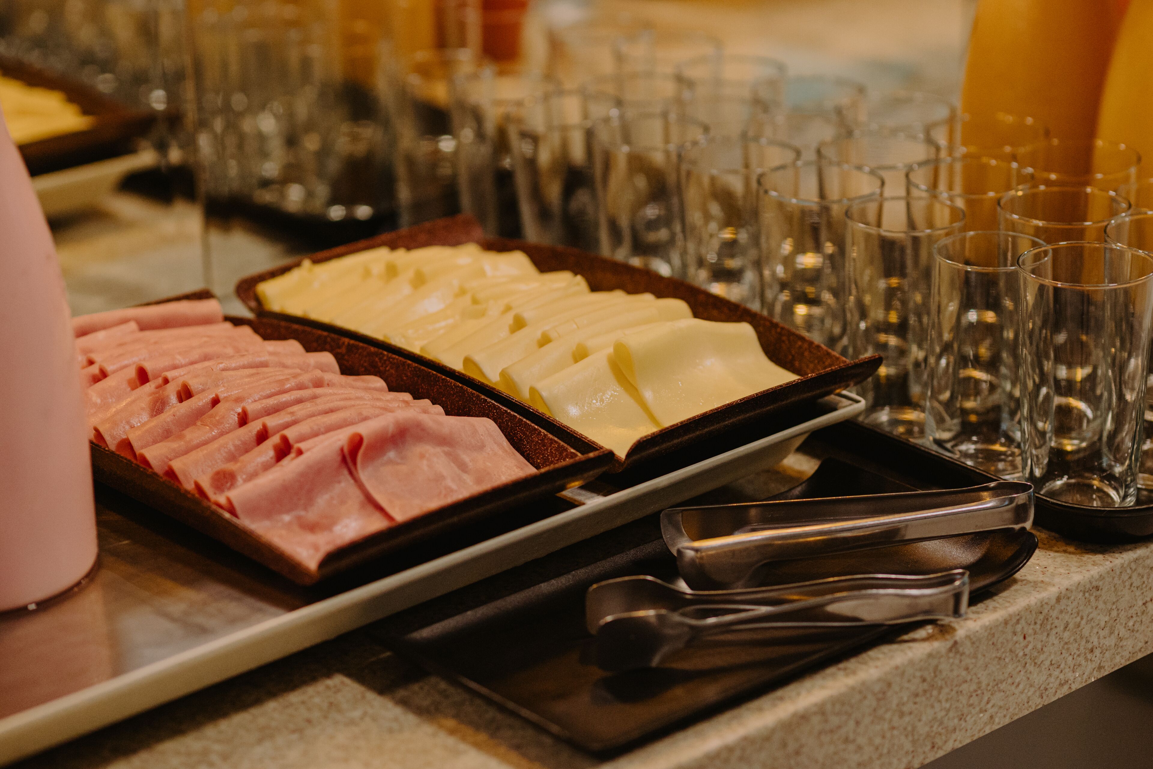 A buffet with various food items and empty glasses on a counter.