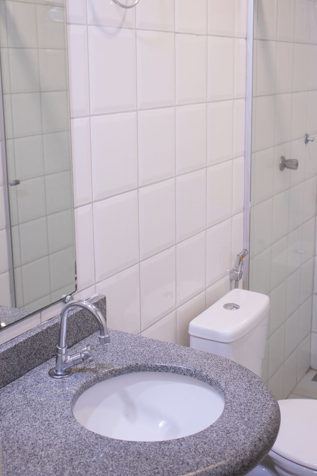 Ein Badezimmer mit einem Granitwaschbecken, einem Spiegel und einer Toilette.