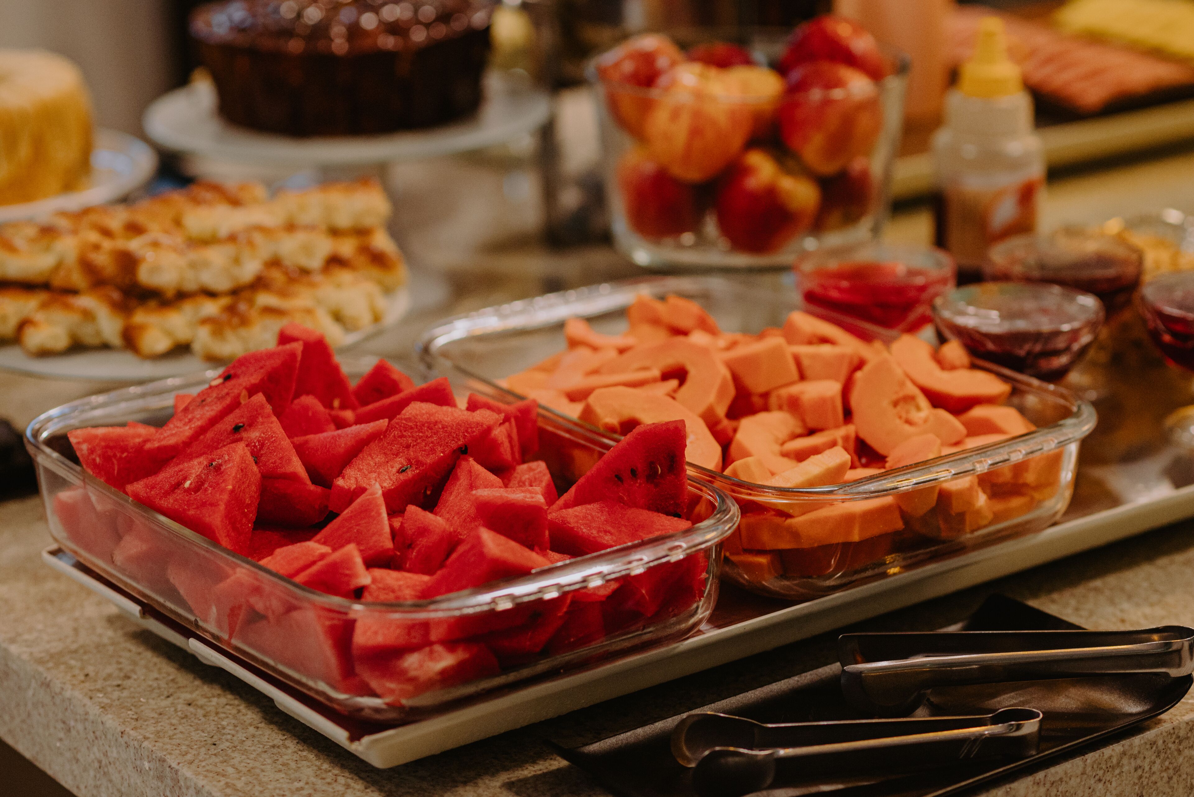 A buffet table with various food items including watermelon, cantaloupe, and other fruits.