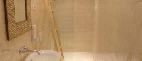 A bathroom with a sink, mirror, and shower.